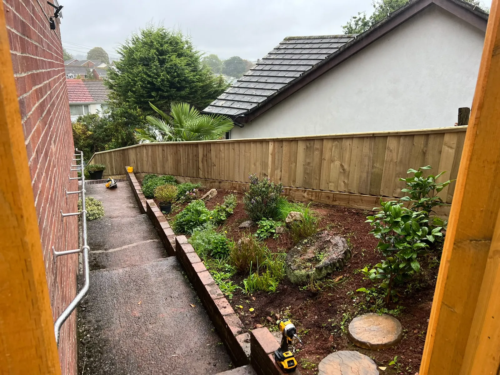 Low feather-edge boundary fence along a garden bed next to a stepped path in Paignton