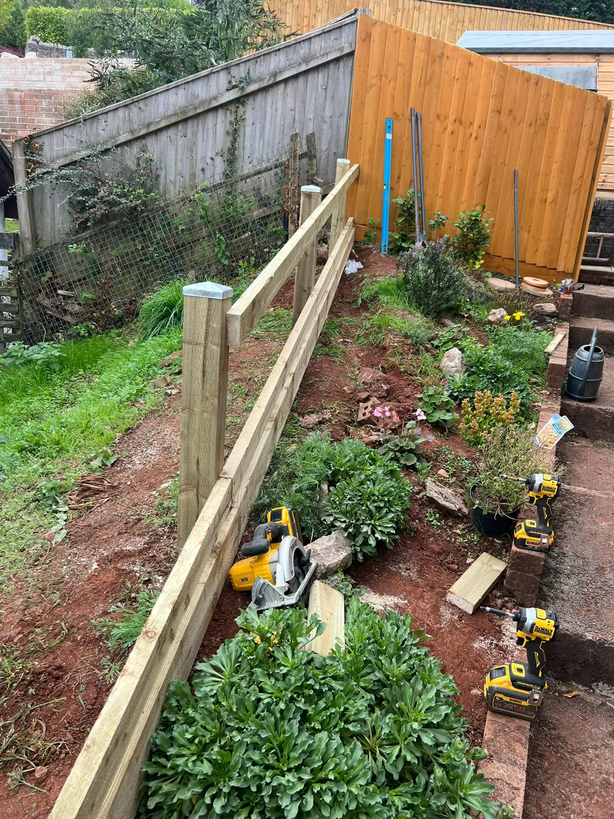 Timber rails and posts following a slope beside a planted bed during a Paignton boundary fence install
