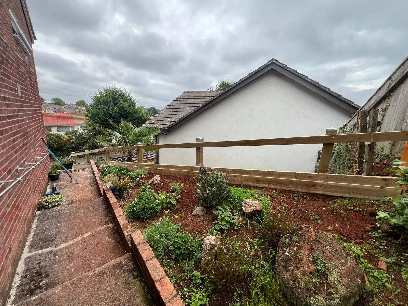 Posts, rails and gravel board for a new low boundary fence along a planted flower bed in Paignton