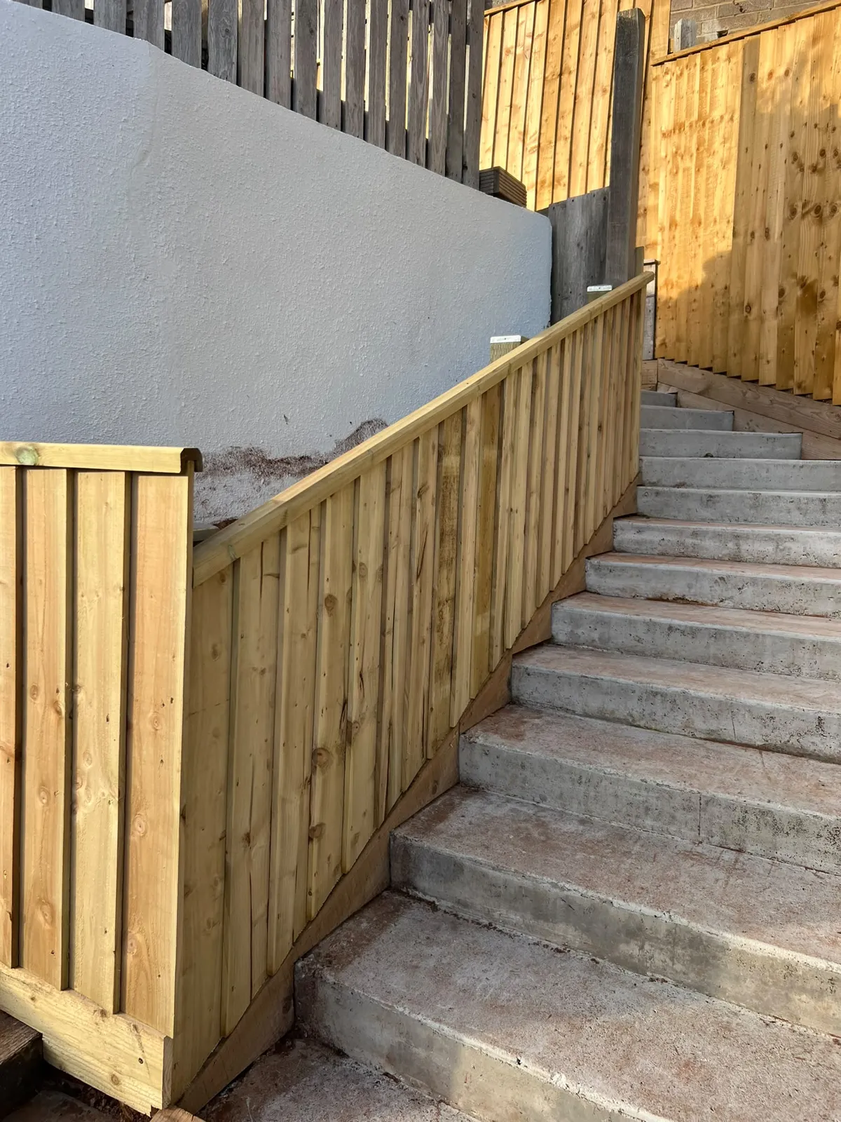 Close view of finished vertical boards and capping rail on a retaining fence beside Paignton garden steps