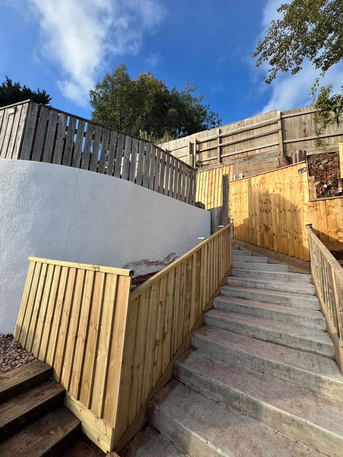 New timber retaining fence with capping rail beside concrete garden steps on a sloping Paignton garden