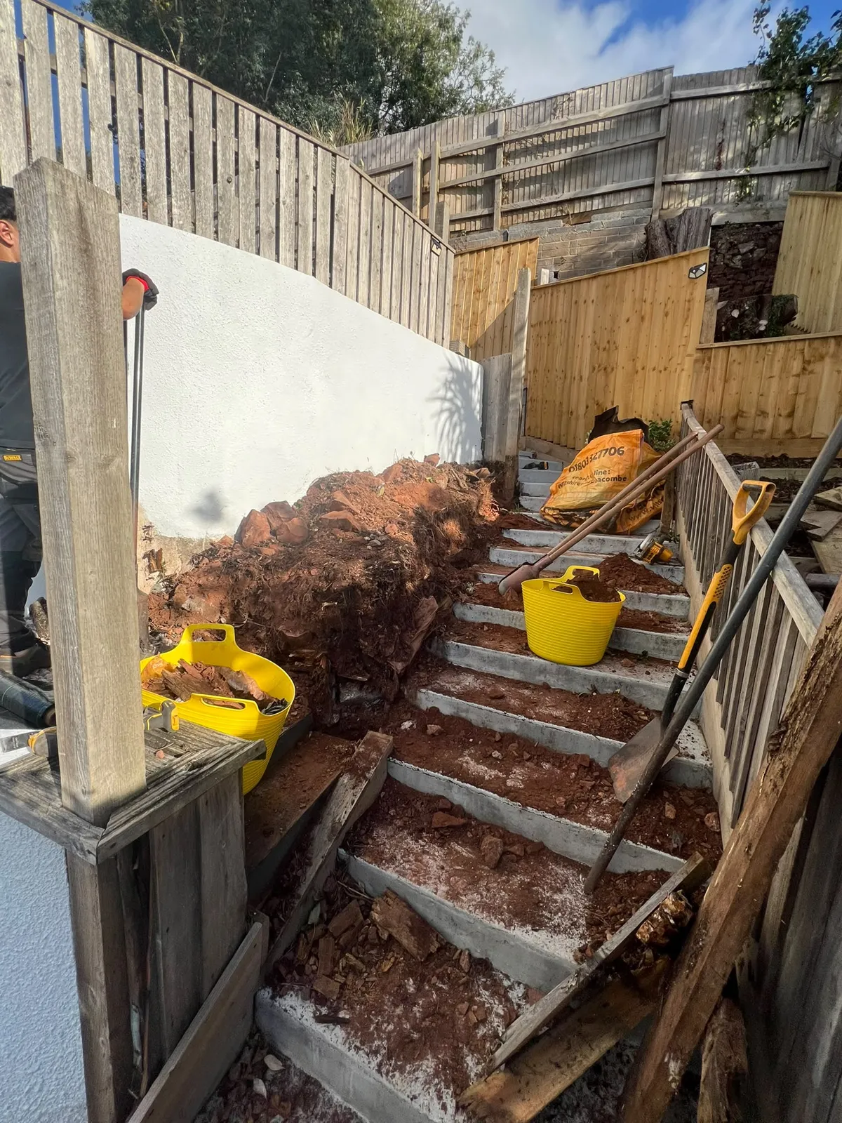 Red Devon soil dug back from garden steps during a retaining fence rebuild in Paignton
