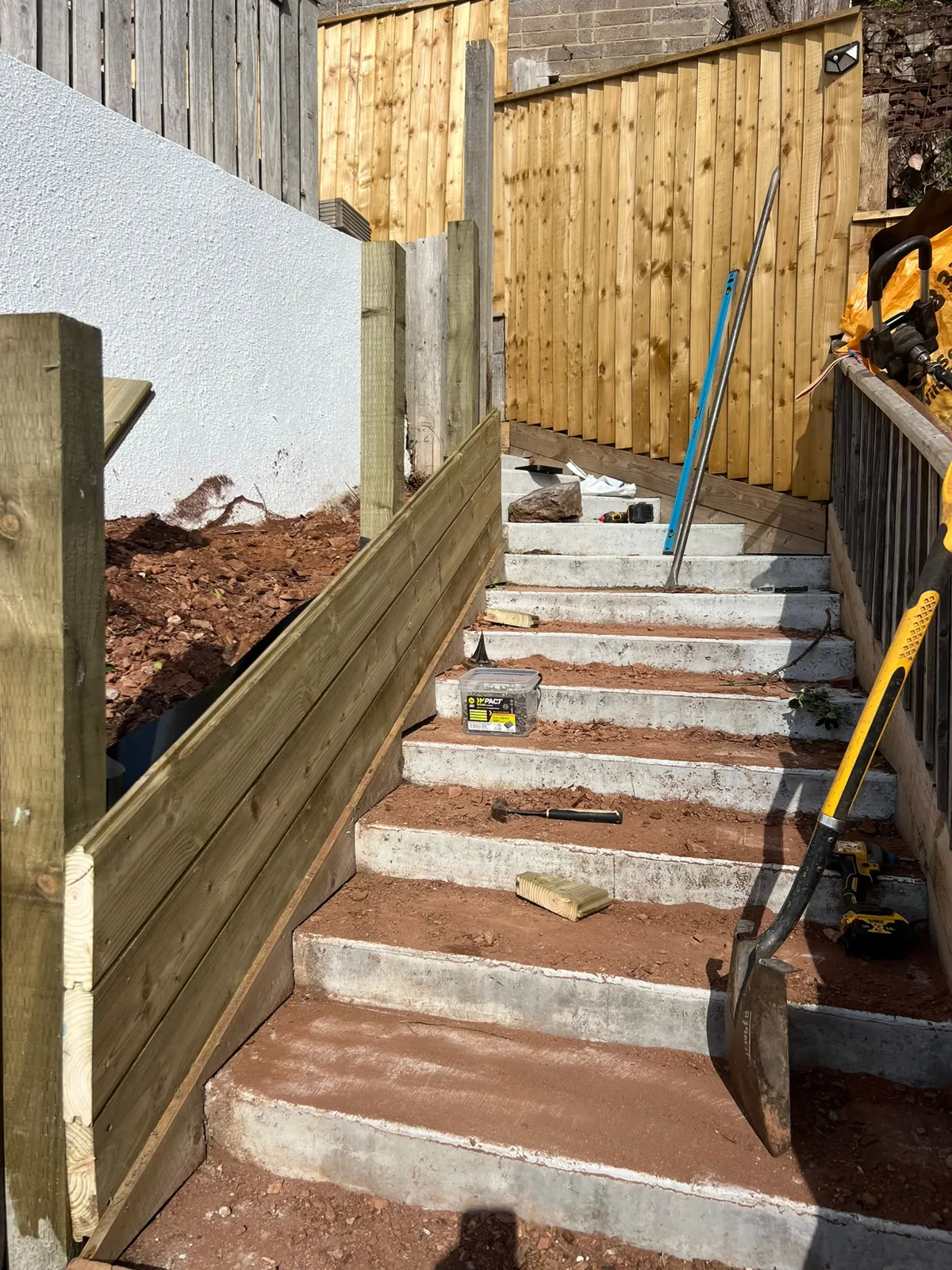 Horizontal tongue and groove timber boards forming a retaining face beside concrete steps in Paignton