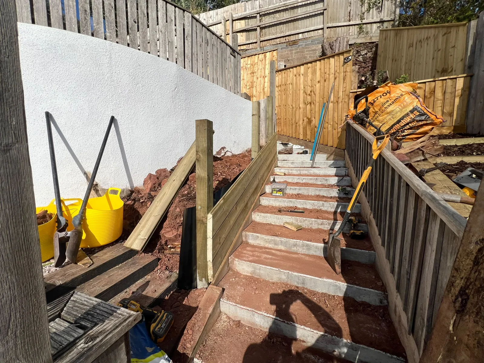 New posts and horizontal tongue and groove boards with black damp-proof membrane behind, Paignton retaining fence