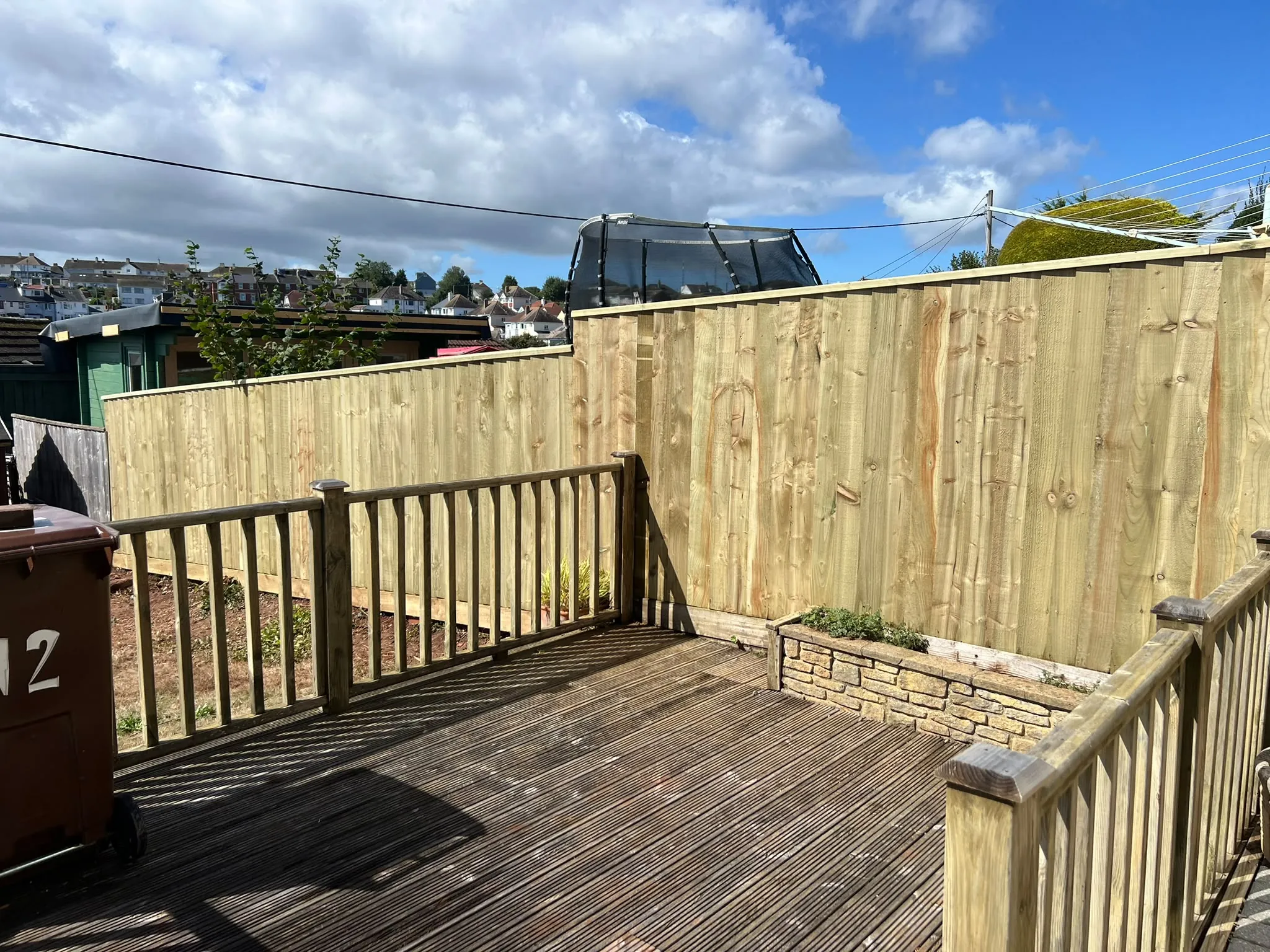 New pressure-treated closeboard fence with capping rail along a Paignton garden boundary beside a timber deck