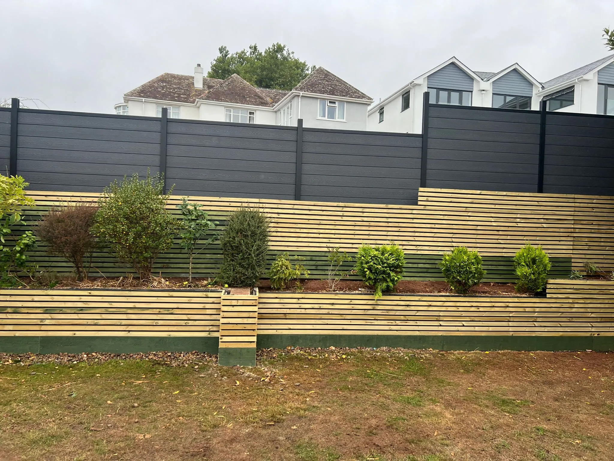The slatted screen running past the raised planters, showing the layered garden edge.